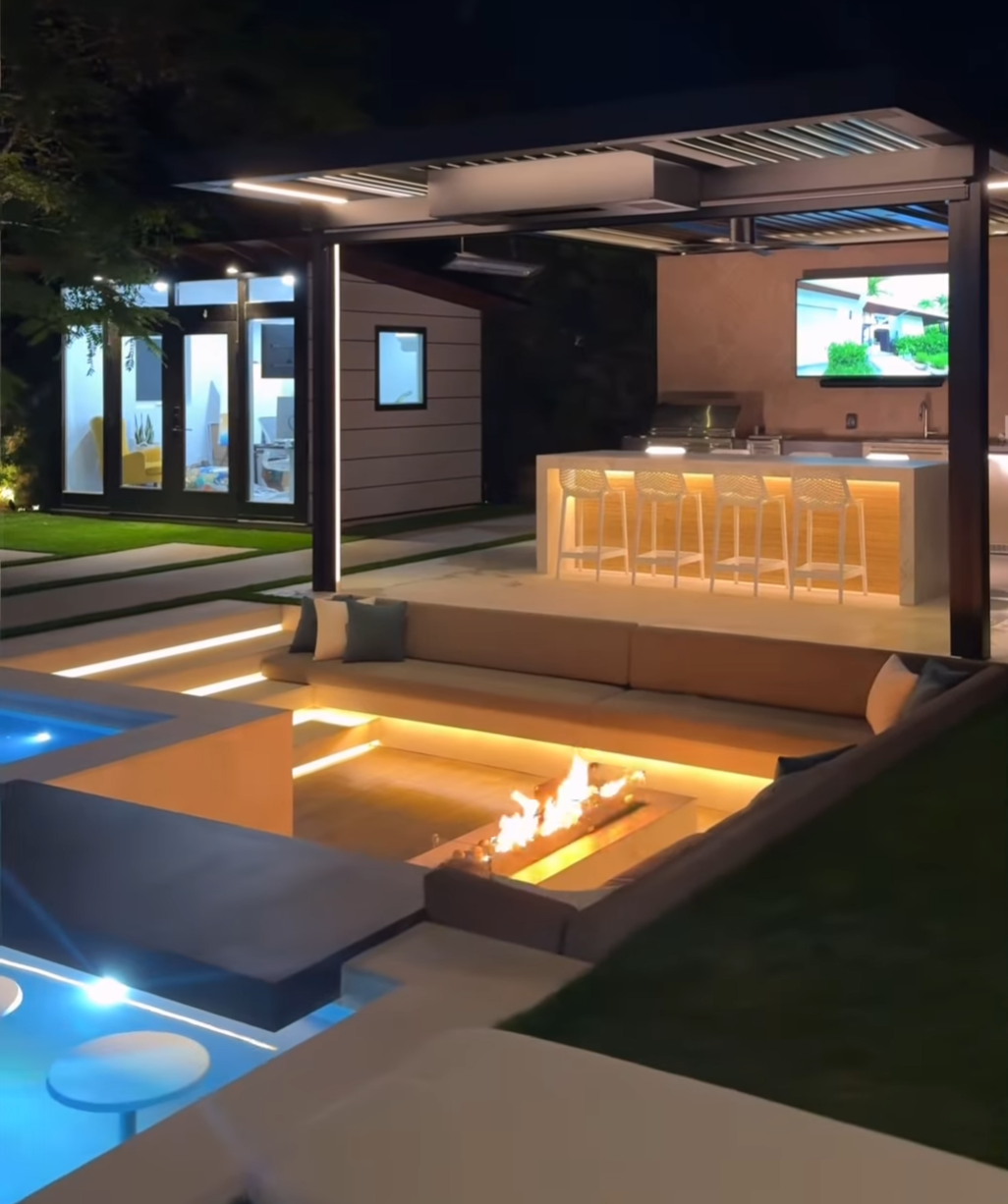 a backyard with a sunken firepit , pool and bar 